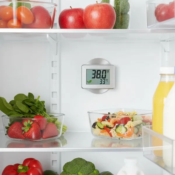 Digital magnetic thermometer showing safe temperature inside a refrigerator with fresh food.